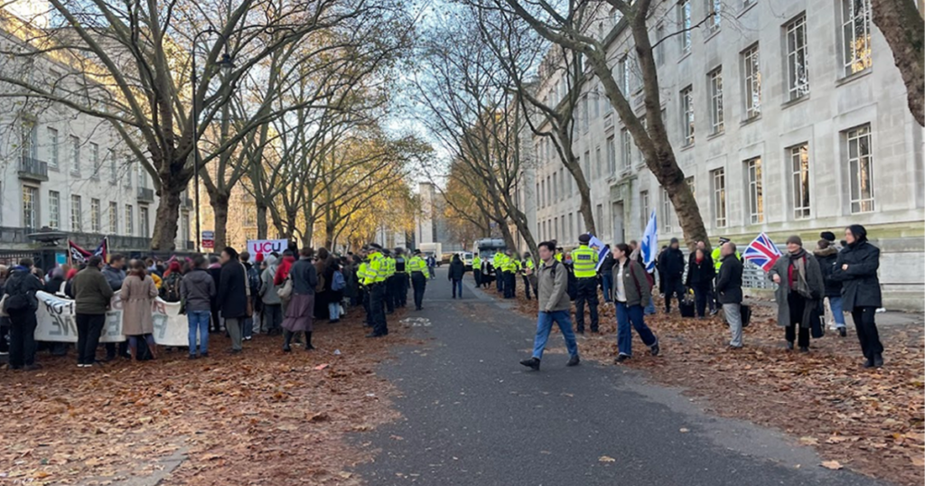 A group of Pro-Palestine protestors demonstrate outside of LSE, with Police at their back. Across the street, a smaller group of Pro-Israel protestors, with Police in front of them.