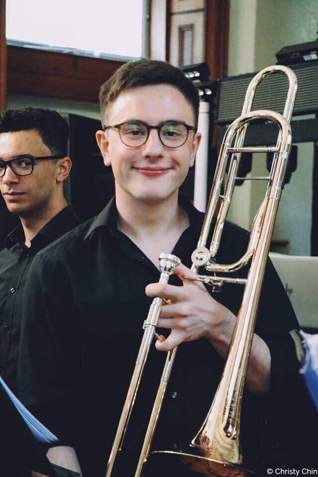 Image may contain: Horn, Brass Section, Trombone, Musical Instrument, Interior Design, Indoors, Person, Human, Accessory, Glasses, Accessories
