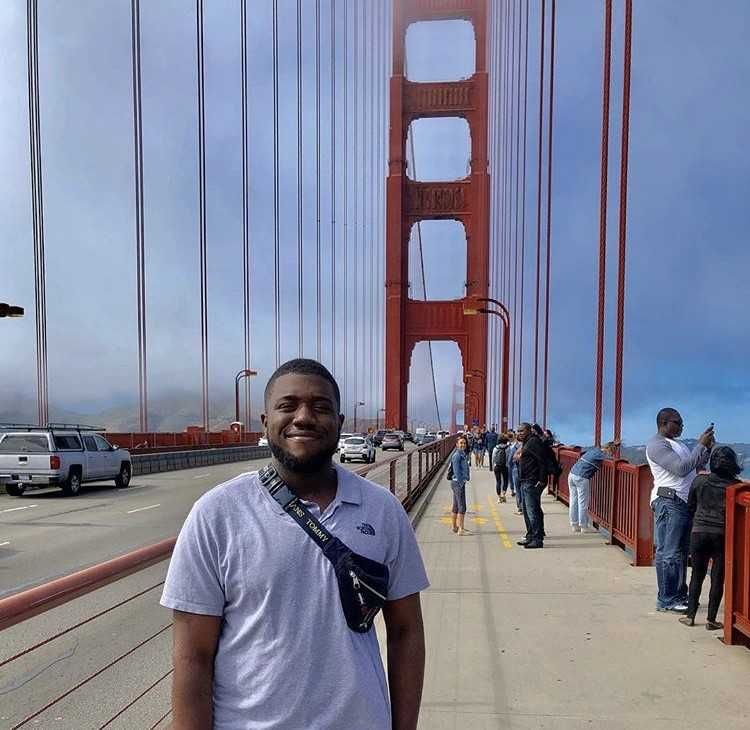 Image may contain: Man, Road, Shorts, Path, Pedestrian, Bridge, Apparel, Clothing, Building, Human, Person