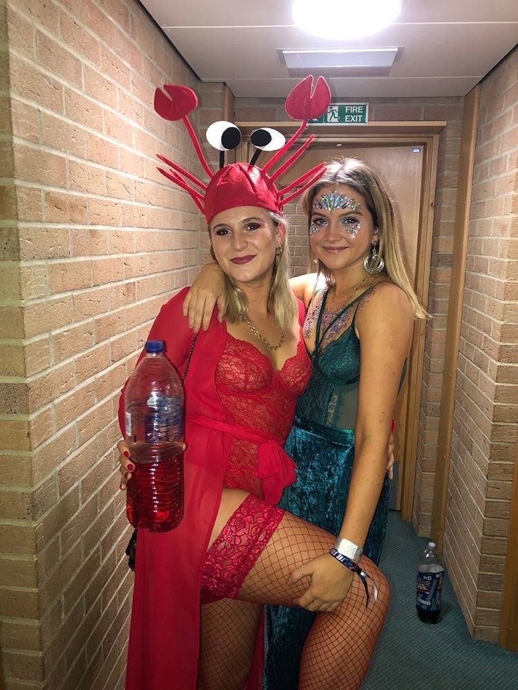 Image may contain: Beverage, Drink, Bottle, Face, Brick, Robe, Gown, Fashion, Evening Dress, Female, Dress, Costume, Human, Person, Clothing, Apparel