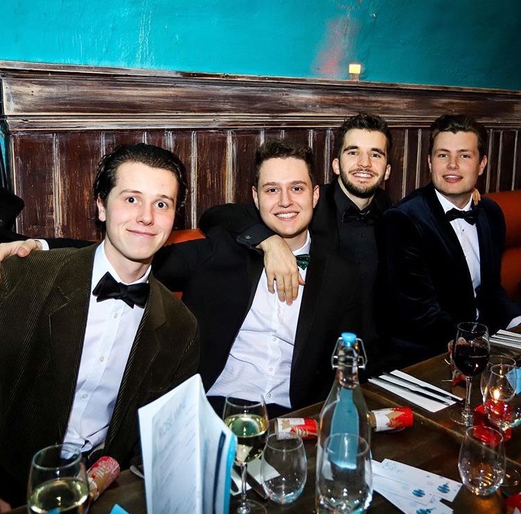 Image may contain: Restaurant, Tuxedo, Liquor, Alcohol, Beverage, Drink, Glass, Overcoat, Clothing, Coat, Suit, Apparel, Bar Counter, Pub, Accessories, Accessory, Tie, Human, Person