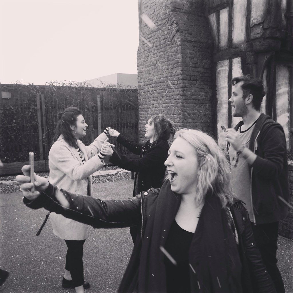A girl takes a selfie whilst her friends have fun behind her