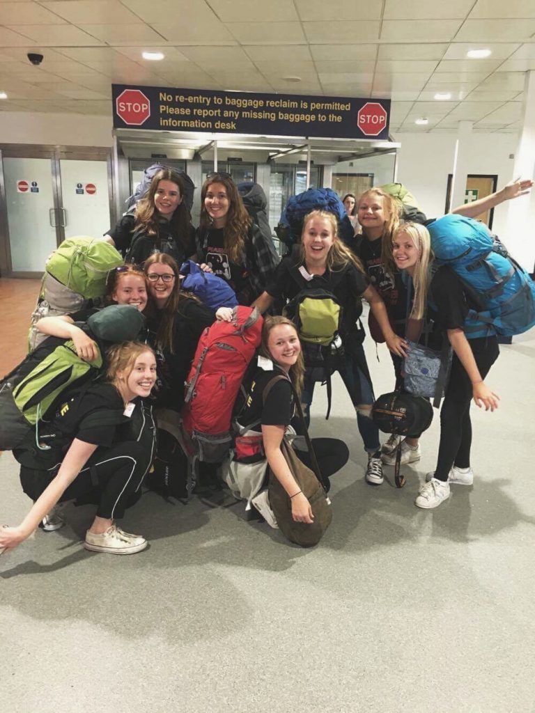 A group of girls with backpacks, posing at an airport
