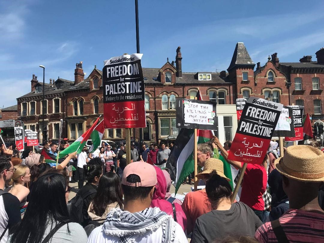 Image may contain: People, Festival, Protest, Text, Parade, Clothing, Hat, Apparel, Crowd, Person, Human