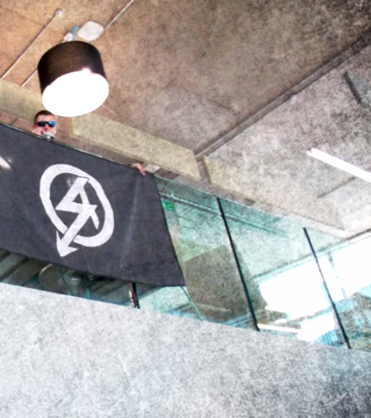 NA Activist Unfurls A Banner With The Groups SA Style Logo In Coventry Students' Union Building
