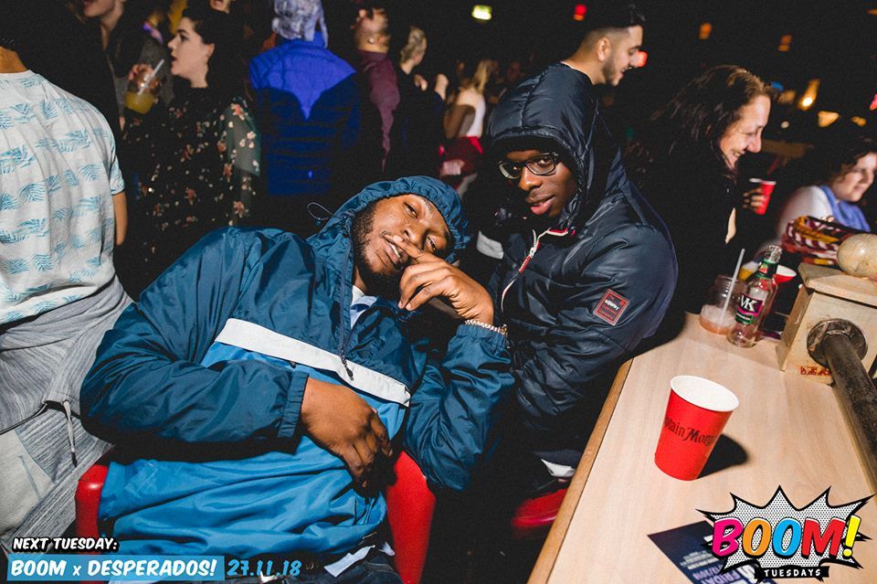 Image may contain: People, Night Club, Dining Table, Furniture, Table, Crowd, Club, Coat, Jacket, Accessory, Accessories, Sunglasses, Clothing, Apparel, Human, Person