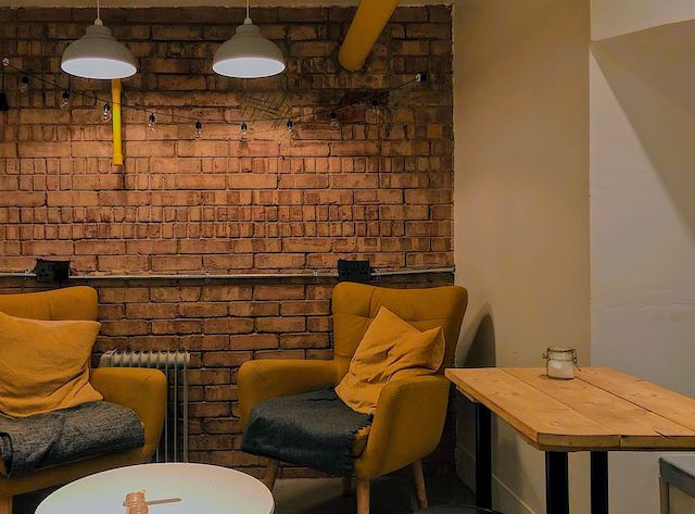 Image may contain: Cafeteria, Cafe, Lighting, Table, Living Room, Couch, Room, Indoors, Home Decor, Restaurant, Chair, Furniture