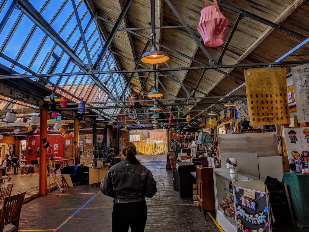 Image may contain: Warehouse, Pants, Apparel, Clothing, Plywood, Home Decor, Shelf, Building, Furniture, Chair, Market, Wood, Lighting, Person, Human