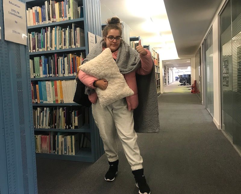 Image may contain: Flooring, Bookcase, Book, Library, Human, Person, Furniture, Footwear, Clothing, Shoe, Apparel, Shelf, Indoors, Room
