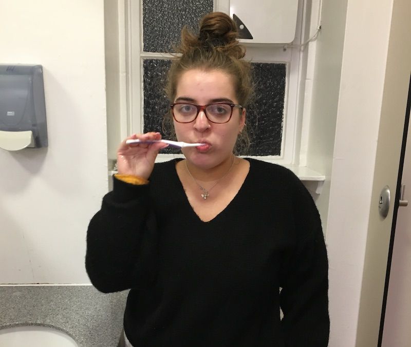 Image may contain: Indoors, Finger, Lip, Mouth, Teeth, Toothbrush, Tool, Brush, Long Sleeve, Accessories, Accessory, Glasses, Apparel, Clothing, Sleeve, Human, Person