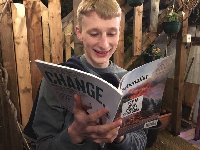 Image may contain: Photo, Photography, Portrait, Plant, Potted Plant, Text, Pottery, Jar, Vase, Chair, Furniture, Smile, Face, Reading, Human, Person, Book