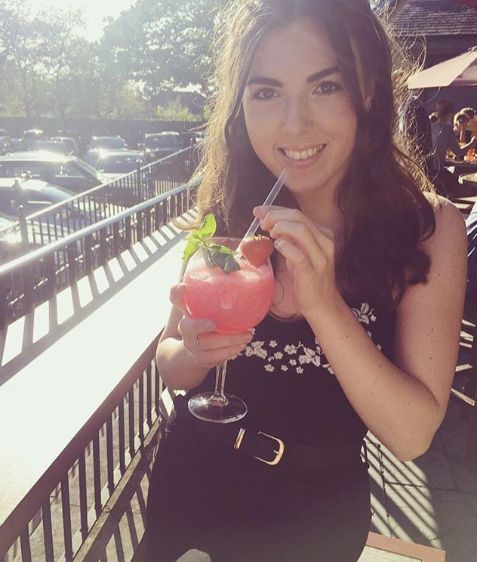 Image may contain: Woman, Portrait, Photography, Photo, Building, Tree, Glass, Outdoors, Clothing, Apparel, Cocktail, Alcohol, Smoothie, Female, Plant, Face, Smile, Human, Person, Drink, Juice, Beverage
