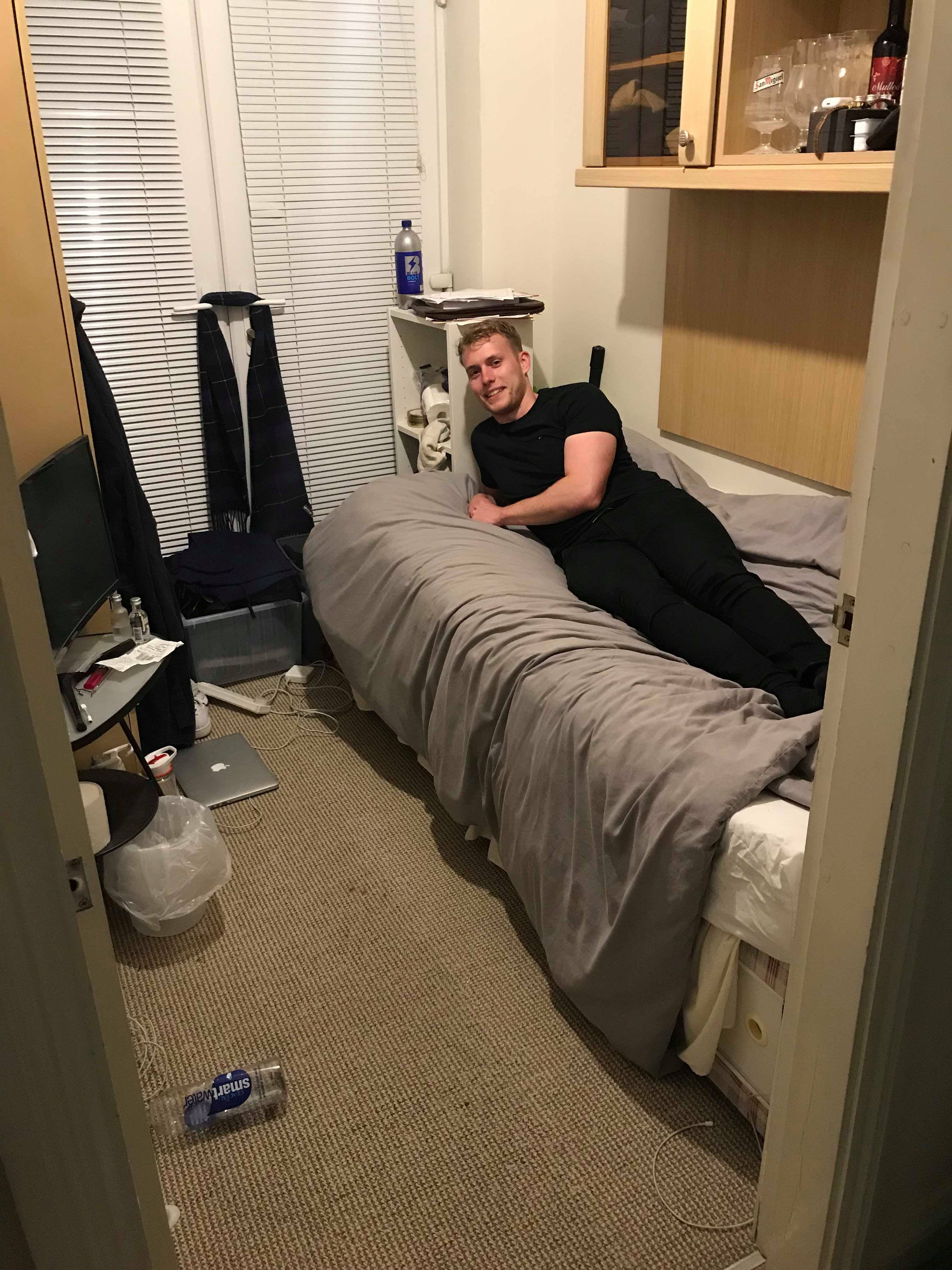 Image may contain: Living Room, Flooring, Shelf, Human, Person, Dorm Room, Bed, Furniture, Bedroom, Indoors, Room