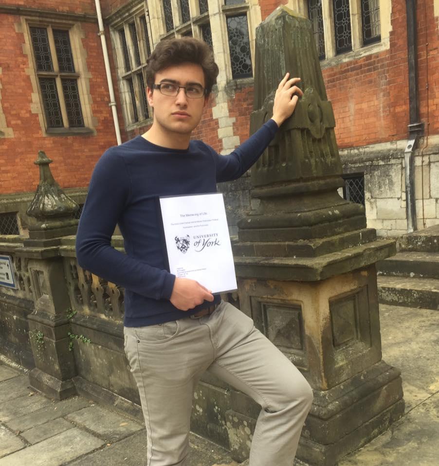 Julian Porch posing with his thesis at Heslington Hall