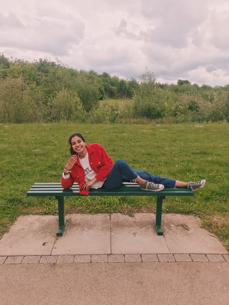 Image may contain: Plant, Grass, Park Bench, Sitting, Bench, Person, Human, Clothing, Apparel, Shoe, Footwear, Furniture