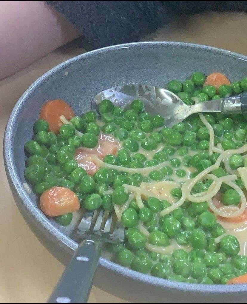 some peas in a pan with spaghetti and hot dogs