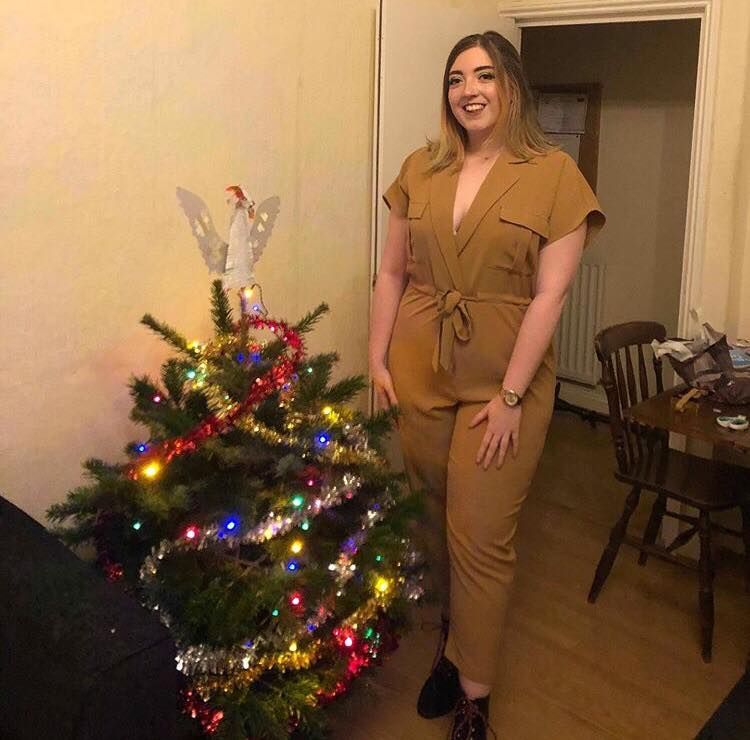 Image may contain: Indoors, Living Room, Room, Couch, Table, Face, Fir, Abies, Pants, Floor, Plywood, Hardwood, Furniture, Chair, Flooring, Wood, Apparel, Clothing, Christmas Tree, Plant, Tree, Ornament, Human, Person