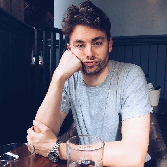 Paul Joseph Watson of Infowars poses at a pub table