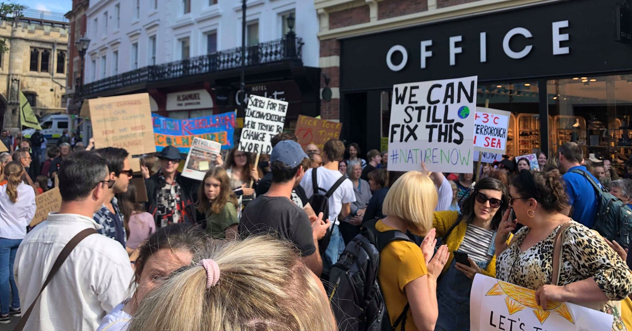 Image may contain: Banner, Protest, Parade, Hair, Text, Crowd, Accessories, Accessory, Sunglasses, Human, Person