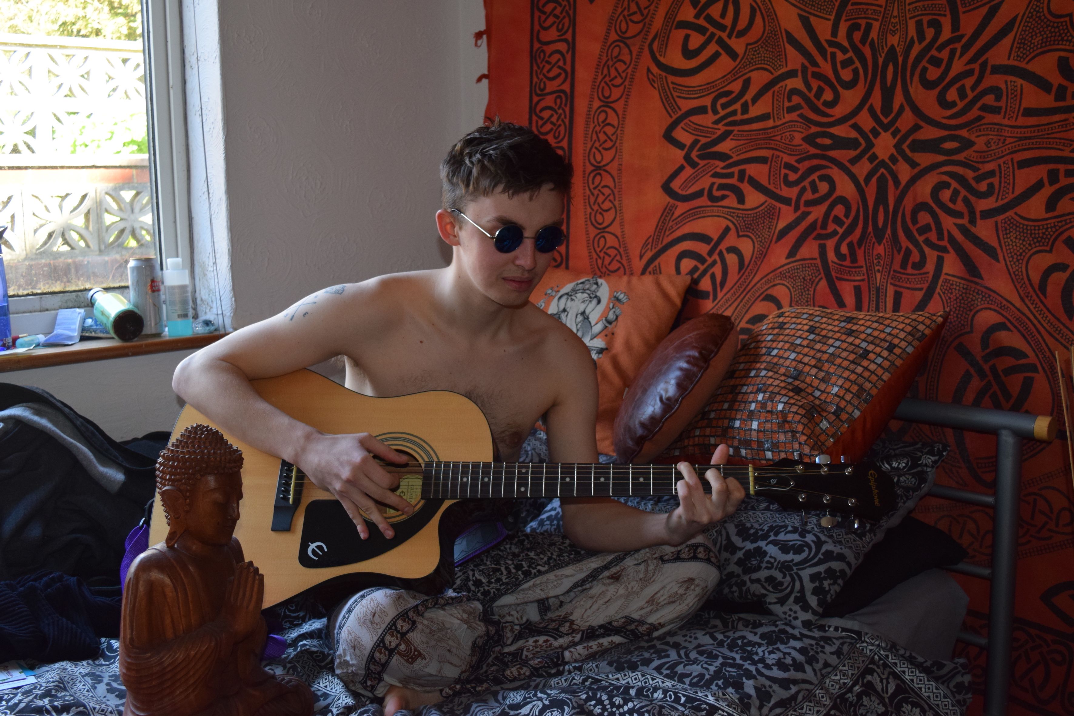 Image may contain: Furniture, Chair, Musical Instrument, Music, Leisure Activities, Guitar, Electric Guitar, Person, People, Human, Worship, Buddha, Art