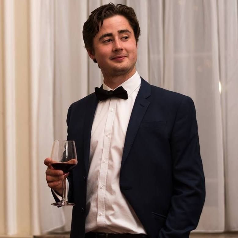 Image may contain: Wine, Red Wine, Drink, Beverage, Alcohol, Tuxedo, Suit, Overcoat, Coat, Clothing, Person, People, Human