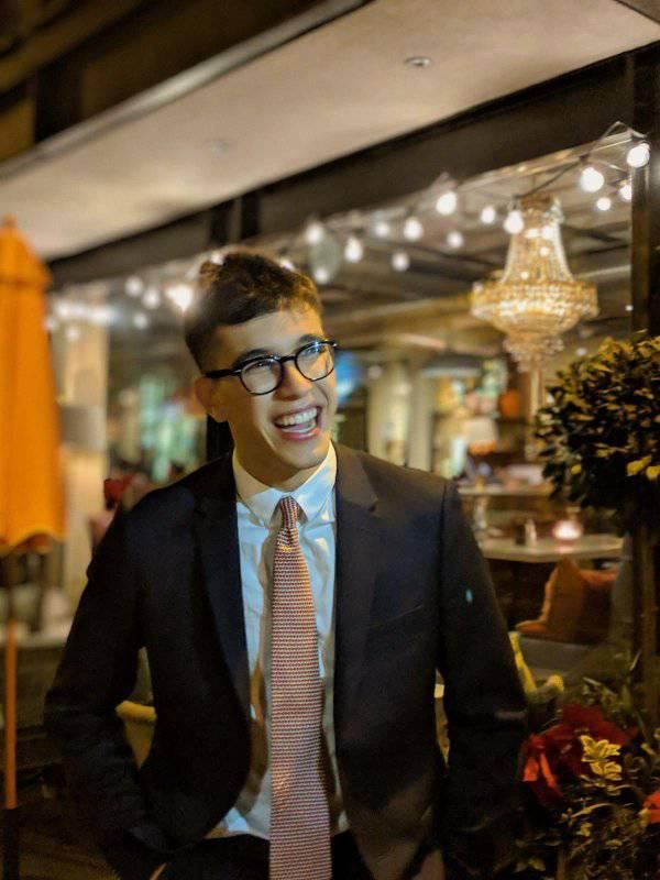 Image may contain: Plant, Man, Face, Tuxedo, Blazer, Jacket, Glasses, Person, Human, Overcoat, Coat, Suit, Clothing, Apparel, Tie, Accessory, Accessories