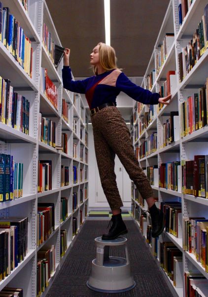 Image may contain: Aisle, Bookcase, Shelf, Furniture, Person, Human, Library, Book, Room, Indoors