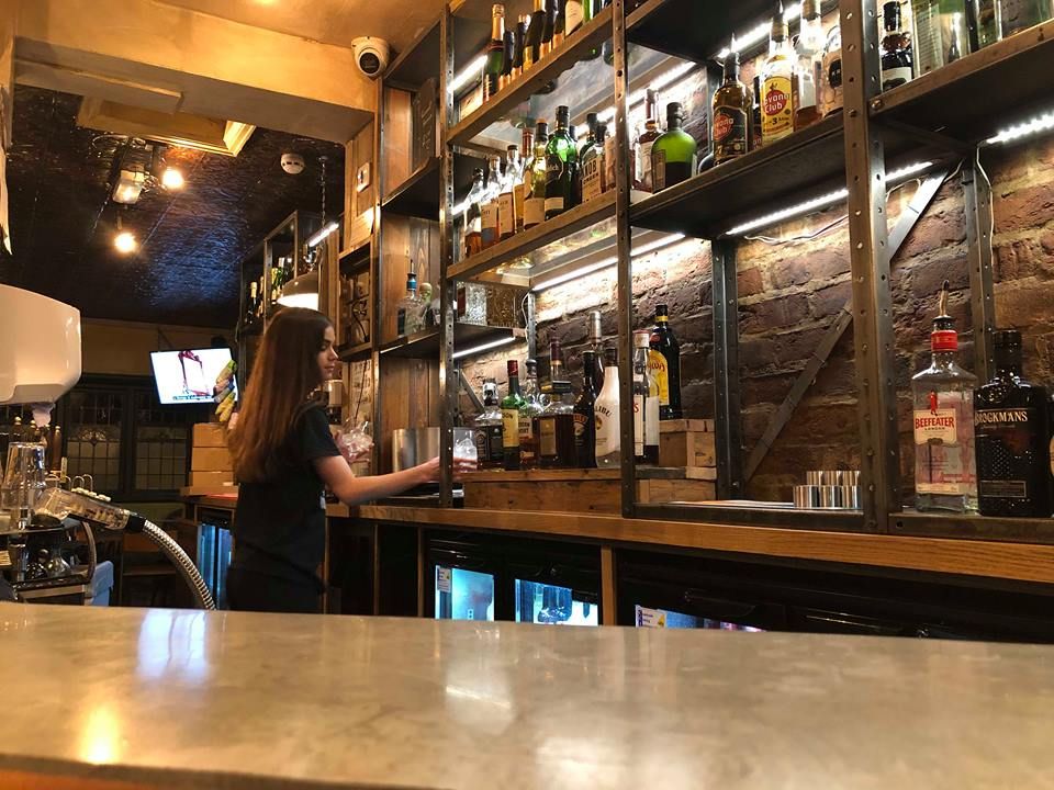 Image may contain: Wood, Lighting, Bar Counter, Pub, Wine Bottle, Beverage, Alcohol, Drink, Wine, Bottle, Person, Human