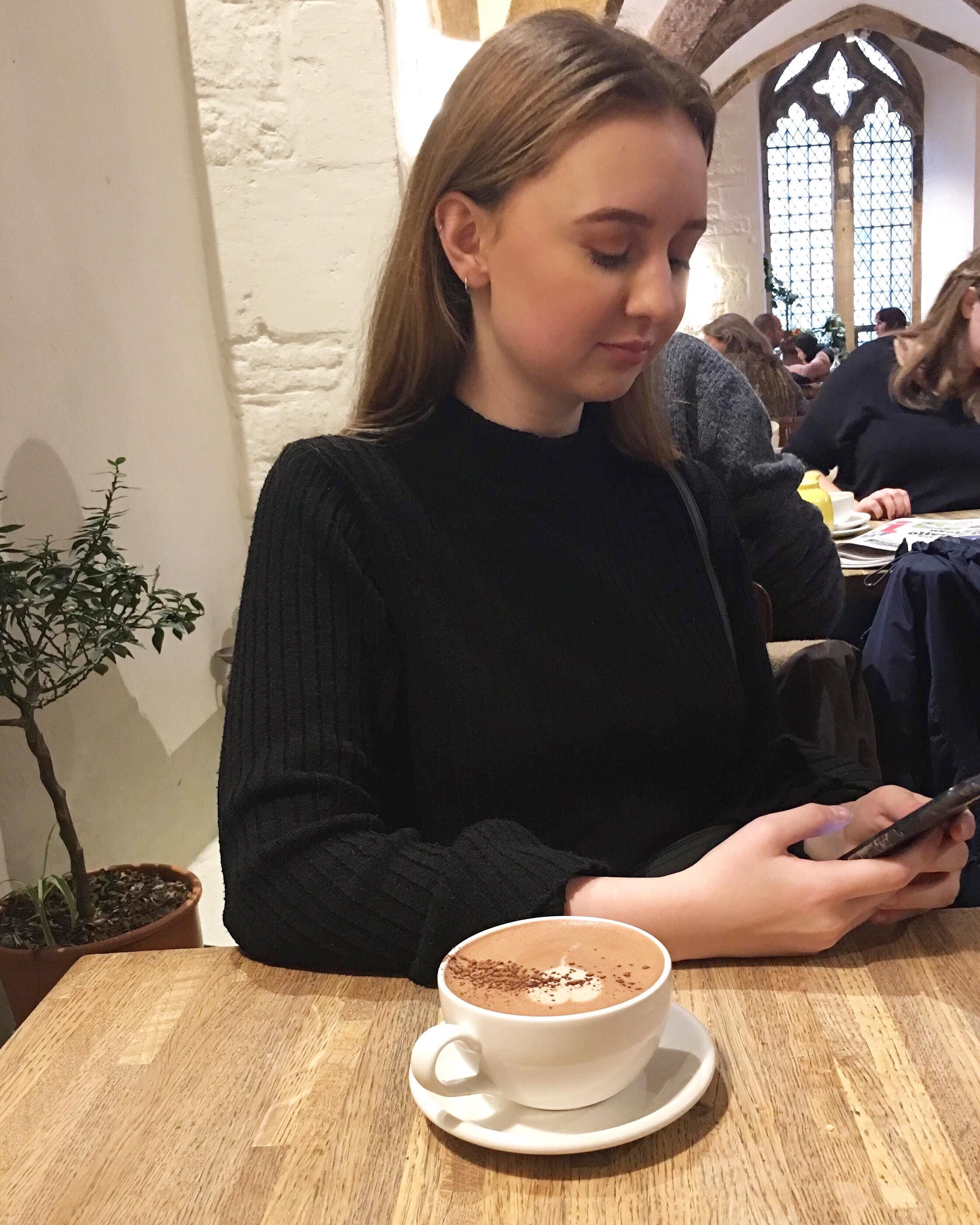 Image may contain: Mobile Phone, Cell Phone, Cup, Coffee Cup, Electronics, Phone, Cafe, Saucer, Pottery, Restaurant, Person, Human