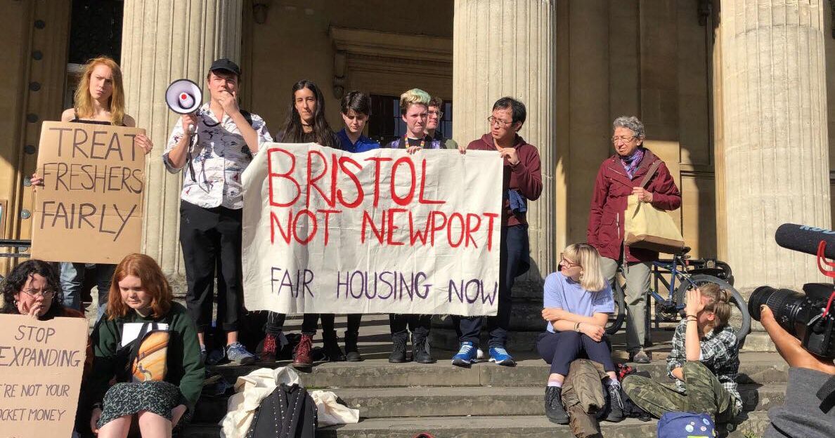 Image may contain: Crowd, Column, Pillar, People, Building, Architecture, Banner, Chair, Furniture, Text, Shoe, Apparel, Clothing, Footwear, Human, Person