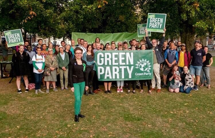 Image may contain: Forest, Land, Nature, Woodland, Outdoors, Female, People, Crowd, Banner, Pants, Tree, Grass, Plant, Vegetation, Clothing, Apparel, Text, Human, Person