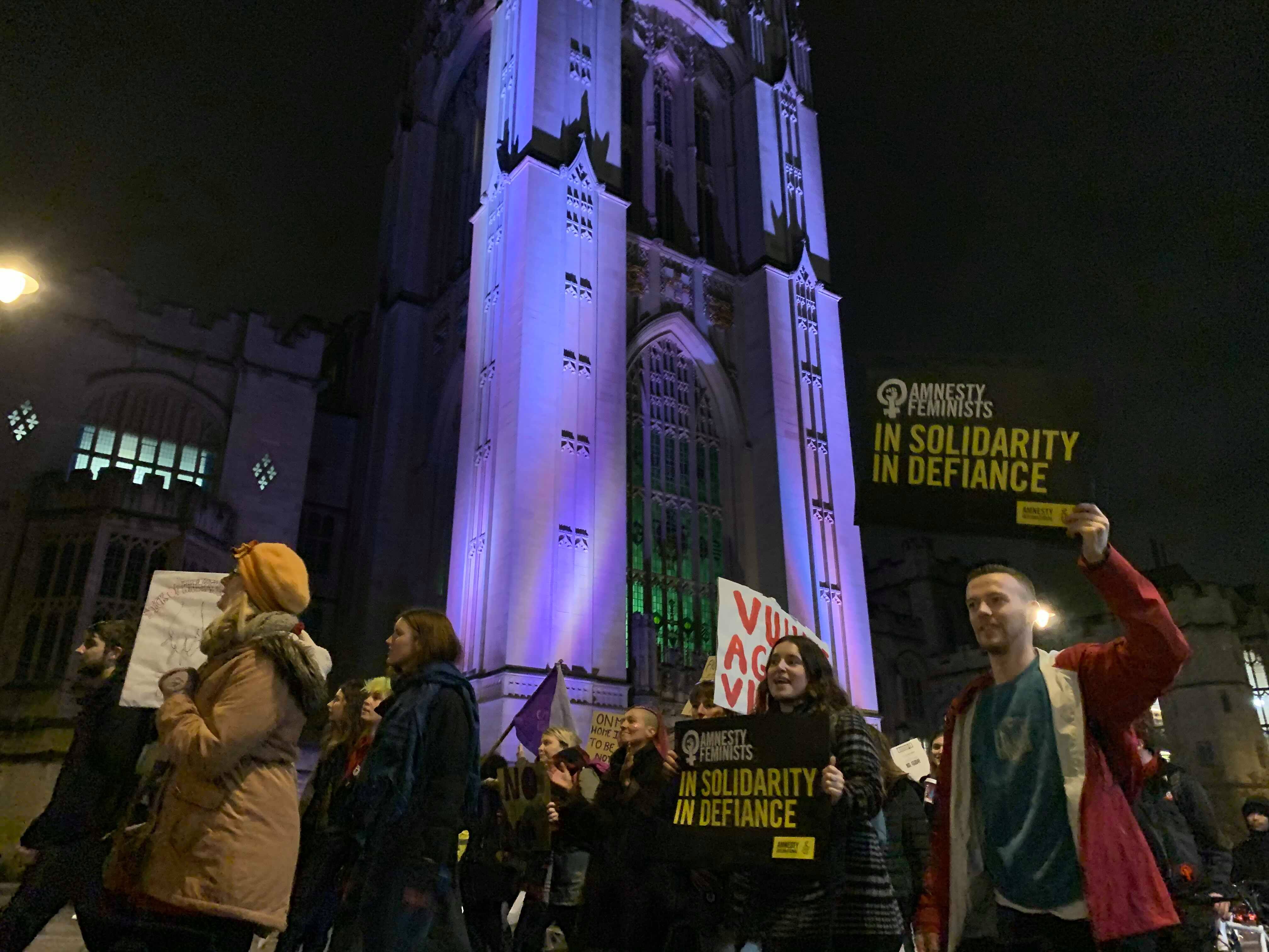 Image may contain: Protest, Parade, People, Pedestrian, Steeple, Spire, Downtown, City, Town, Tower, Urban, Building, Architecture, Crowd, Person, Human