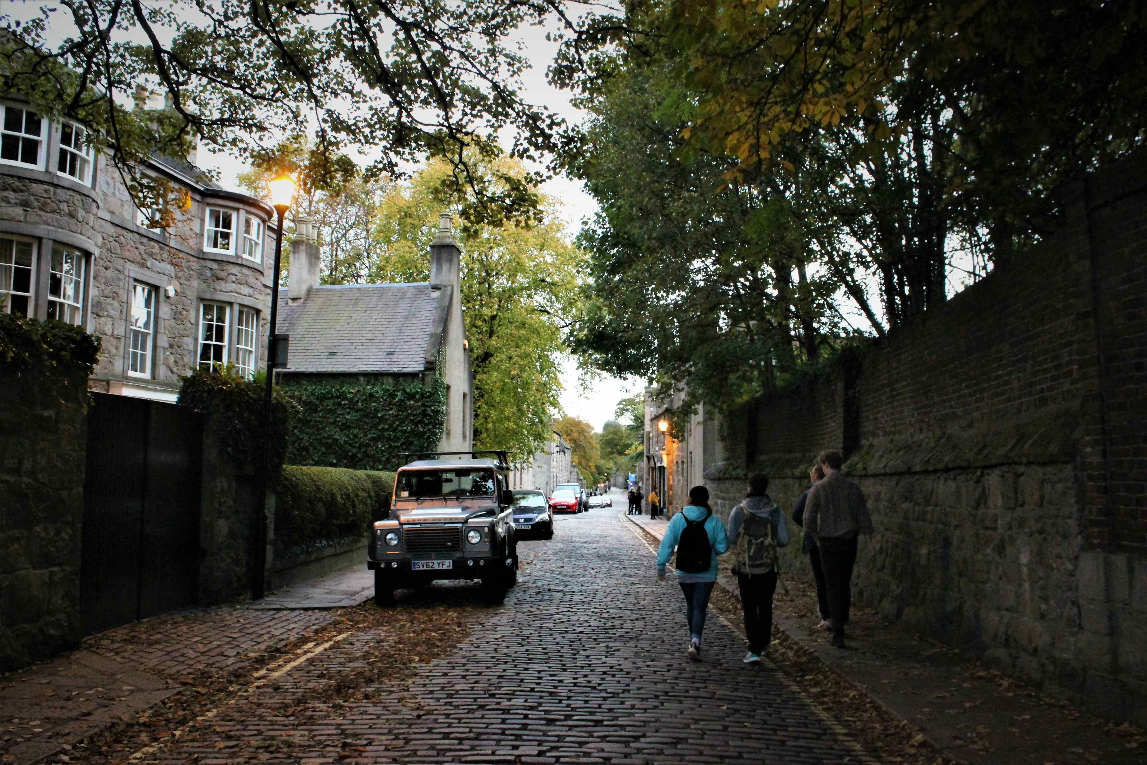 Image may contain: Offroad, Walkway, Pavement, Cobblestone, Housing, Cottage, Building, Walking, Leisure Activities, Town, Street, Road, Alleyway, Alley, Vehicle, Jeep, Car, Human, Person, People