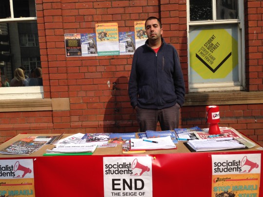 Joe, a Socialist Student, stands. By the stand.