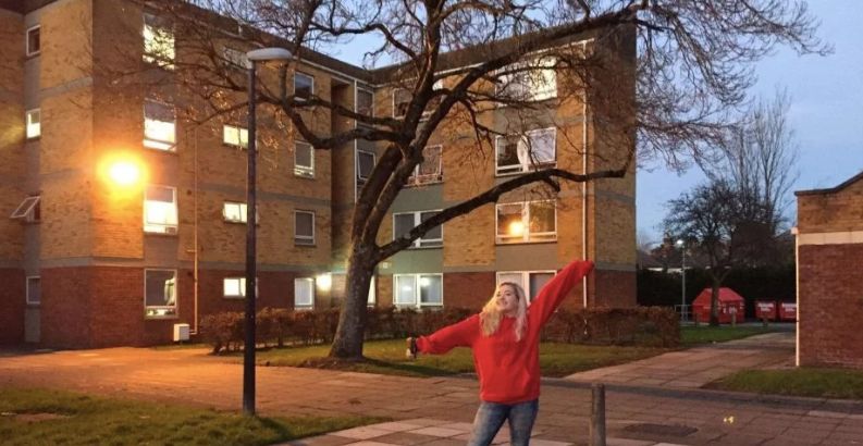 Image may contain: Campus, Grass, Apartment Building, Tree, Plant, High Rise, Town, City, Denim, Jeans, Human, Person, Housing, Neighborhood, Urban, Building, Apparel, Pants, Clothing