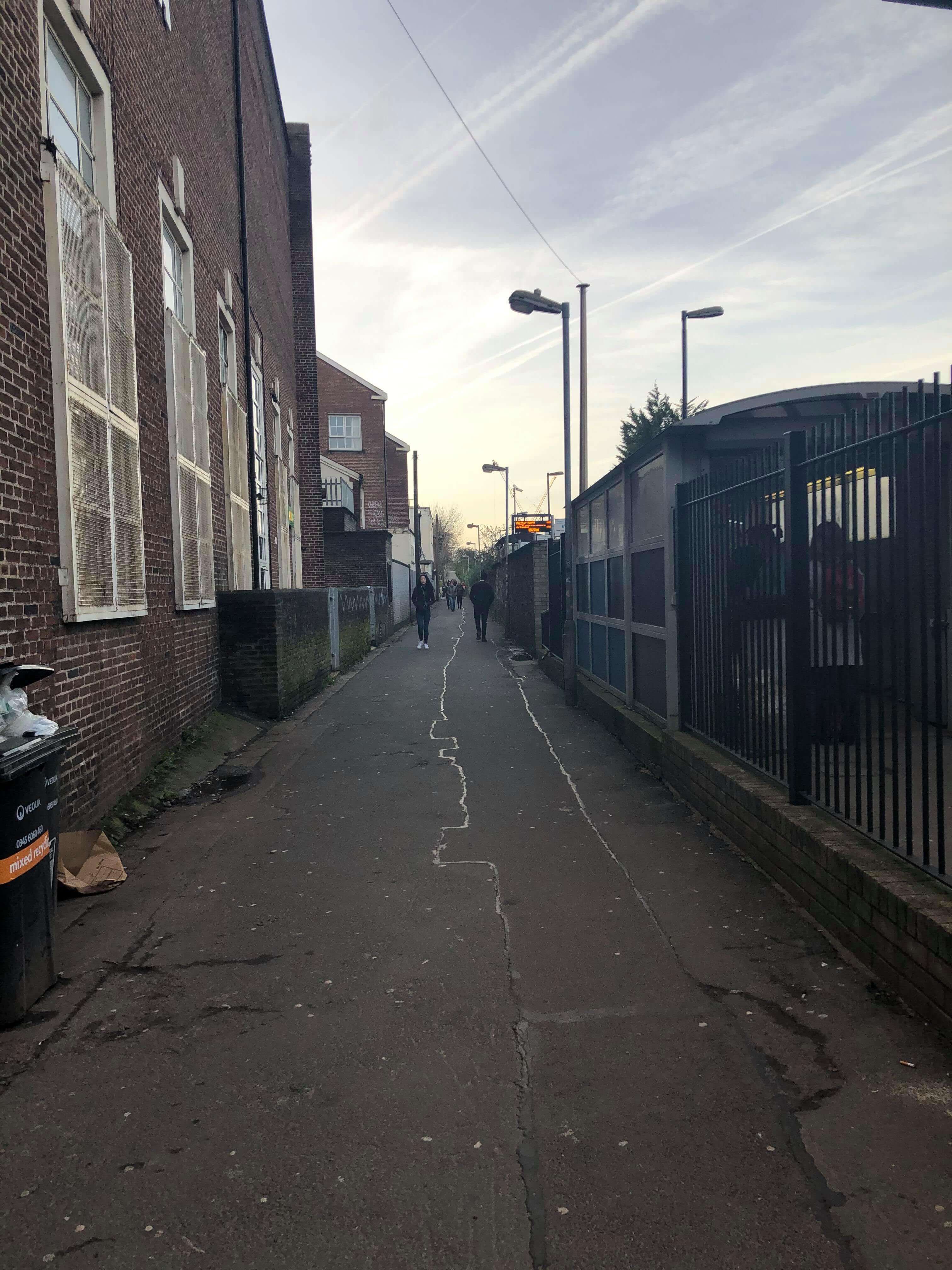 Image may contain: Walkway, Path, Alleyway, Alley, Vehicle, Transportation, Train, Asphalt, Tarmac, Person, Human, Road, Town, Building, Street, Urban, City