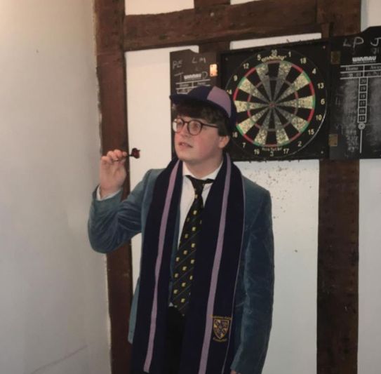 Image may contain: Game, Darts, Suit, Overcoat, Coat, Apparel, Clothing, Human, Person, Accessories, Accessory, Tie