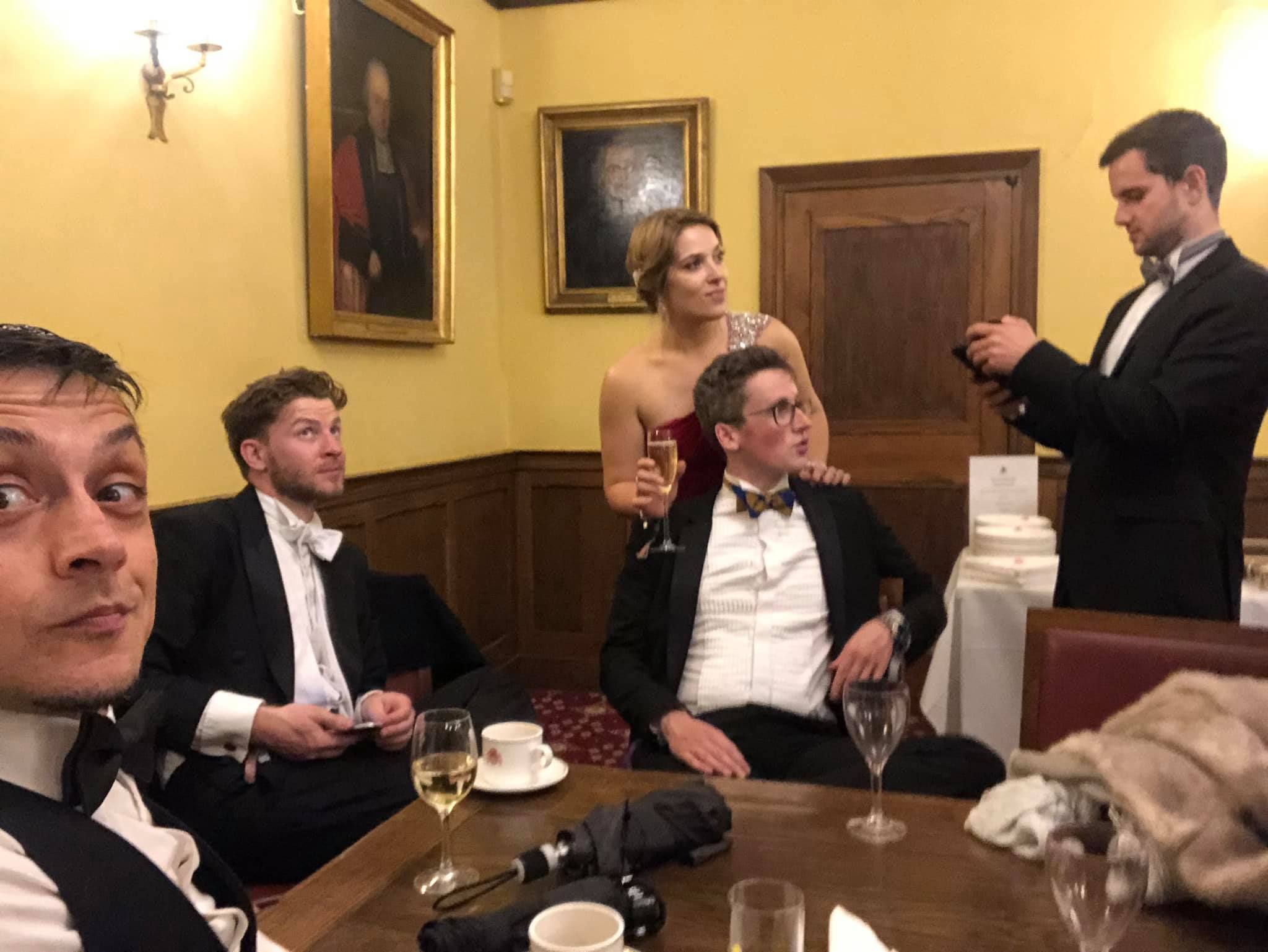 Image may contain: Indoors, Room, Drink, Beverage, Bar Counter, Dining Table, Pub, Table, Sitting, Glass, Tuxedo, Restaurant, Furniture, Clothing, Overcoat, Apparel, Coat, Suit, Human, Person