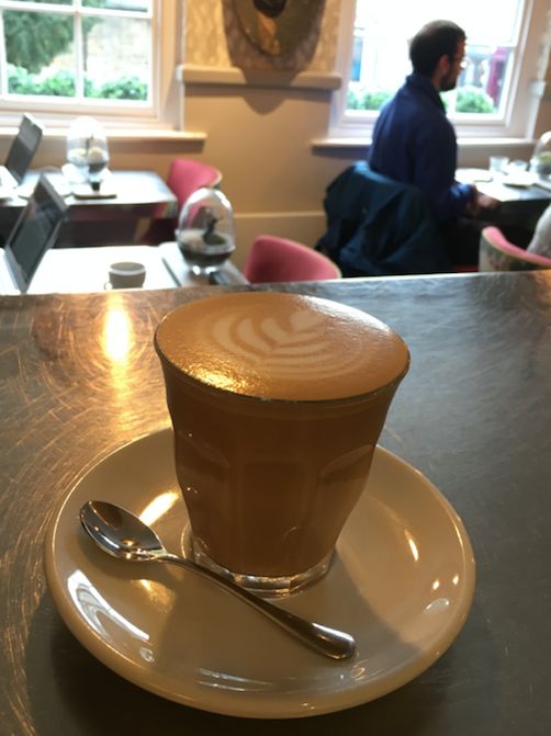 Image may contain: Cafe, Restaurant, Beverage, Latte, Drink, Table, Furniture, Cup, Coffee Cup, Saucer, Pottery, Human, Person, Spoon, Cutlery