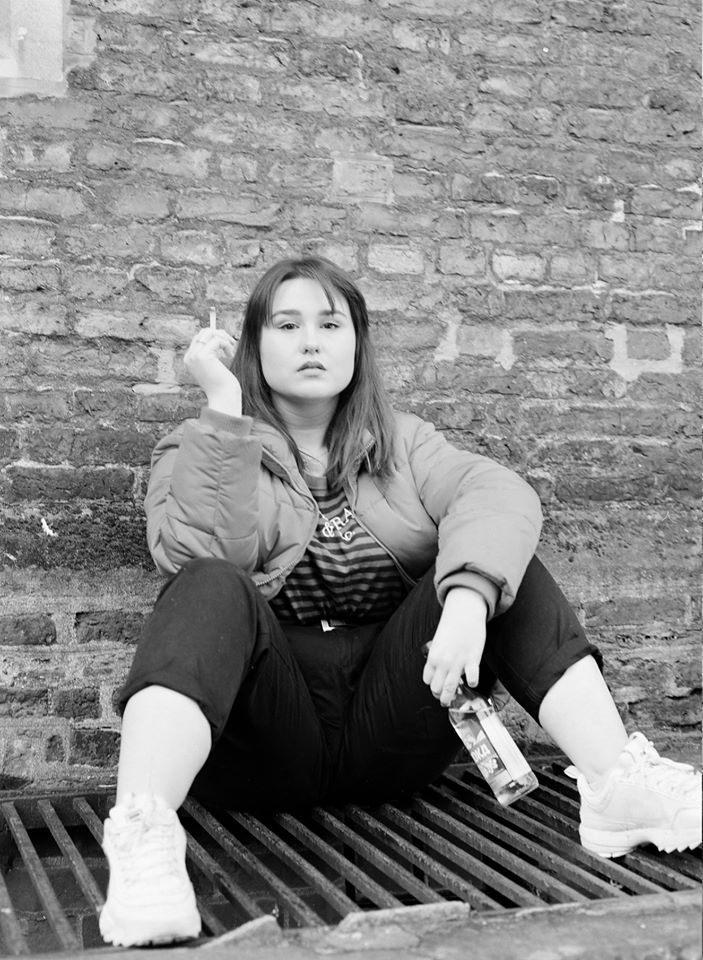 Image may contain: Girl, Footwear, Wall, Bench, Furniture, Female, Apparel, Clothing, Person, Human, Brick