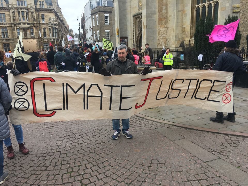 Image may contain: Word, Pedestrian, Parade, Protest, Banner, Crowd, Text, Person, Human, Shoe, Apparel, Footwear, Clothing