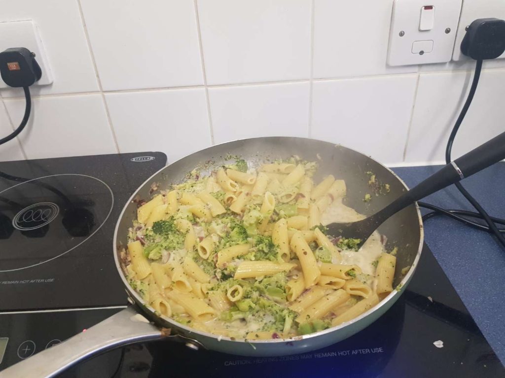Pan filled with pasta, broccoli, onion and cream
