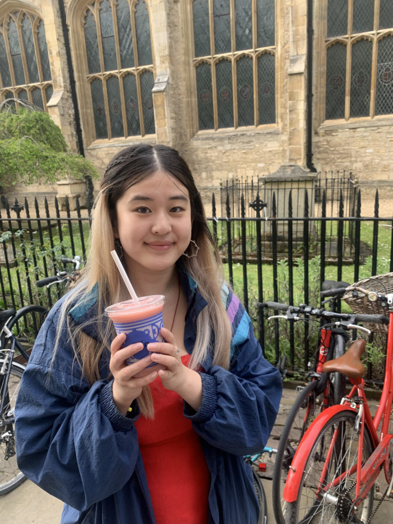 Girl holding a Caffè Nero fruit booster and smiling