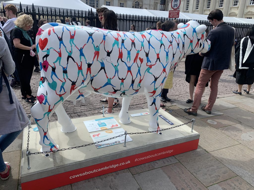 White cow with many stick figures holding hands painted on it