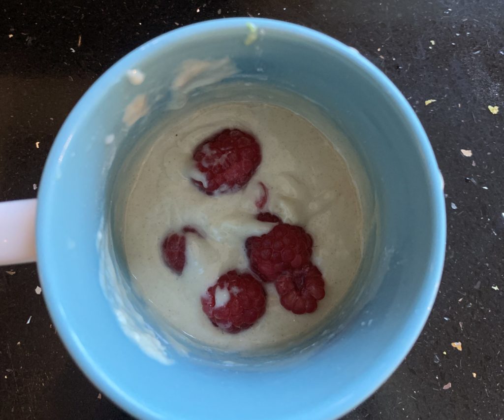 Mug with cake mix and raspberries inside