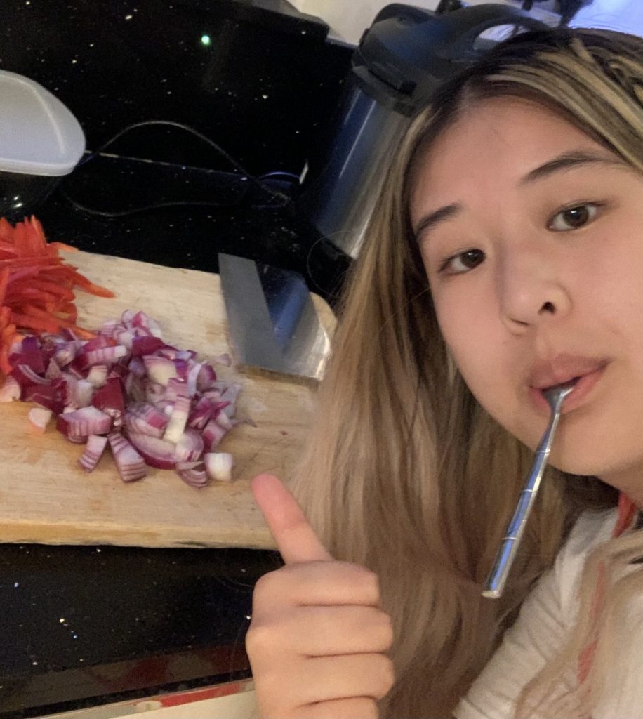 Girl with a spoon in her mouth chopping onions