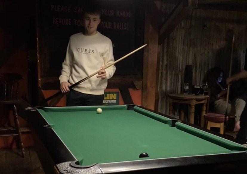 A boy stood over a pool table