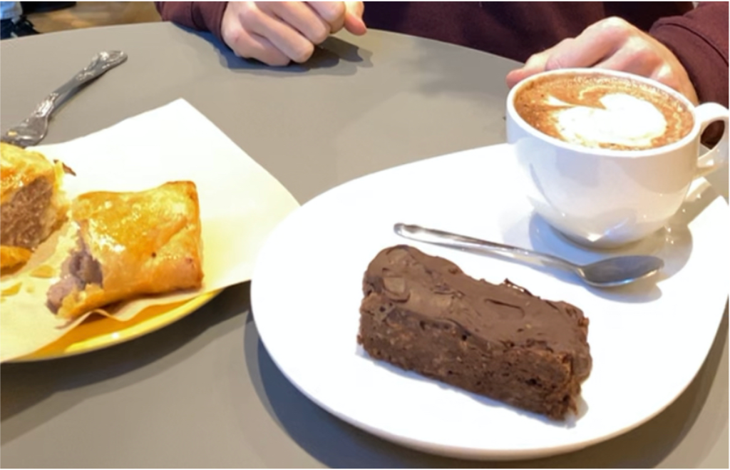 A brownie, coffee and sausage roll in a coffee shop