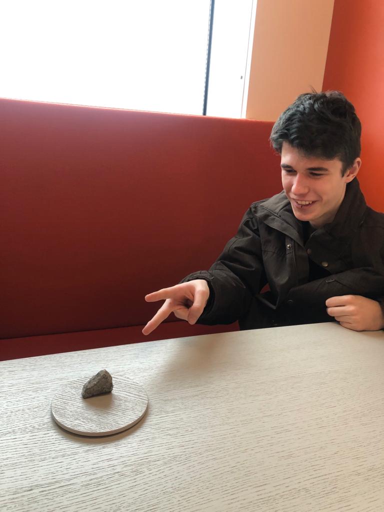 David playing scissors against a rock on a pedestal.