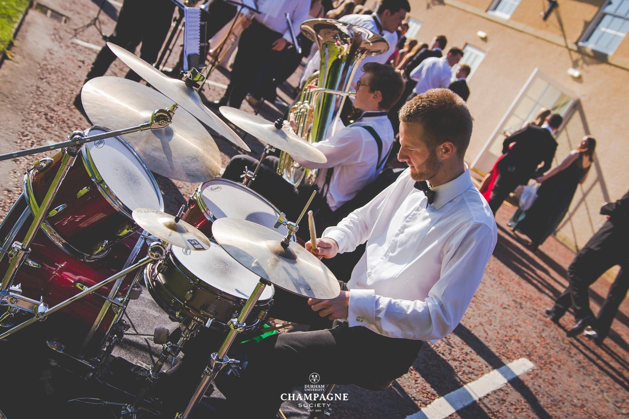 Image may contain: Performer, Percussion, Musician, Drummer, Crowd, Bench, Tuba, Musical Instrument, Music, Horn, Euphonium, Brass Section, Tango, Leisure Activities, Dance Pose, Dance, Person, People, Human